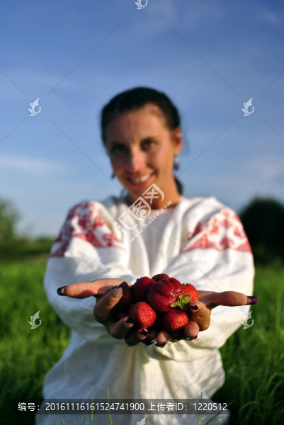 俄羅斯女孩在傳統(tǒng)的服裝舉行草莓在手