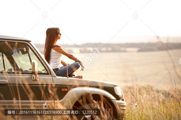 女人坐在汽車的引擎蓋上