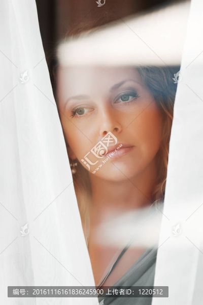 美麗的女人透過窗戶看。