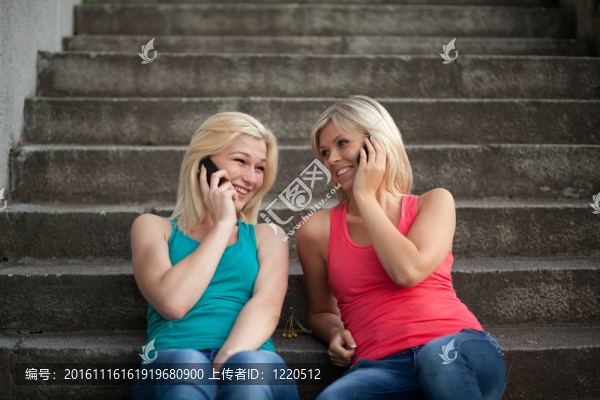 兩個女孩坐在臺階上用手機聊天