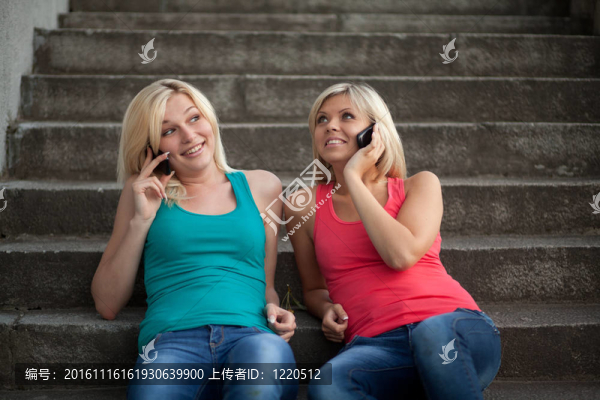 兩個(gè)女孩坐在臺(tái)階上用手機(jī)聊天