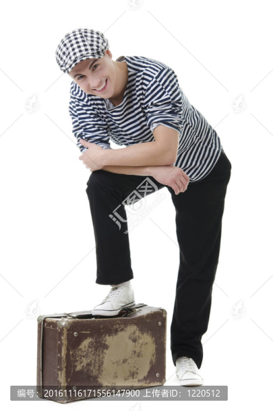 看頑皮英俊的年輕男子在時(shí)尚條紋連衣裙和帽子與手提箱