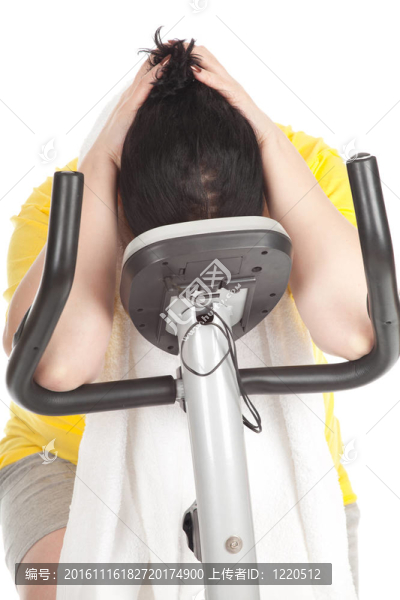 疲勞超重；穿黃色襯衫的胖女人在固定健身自行車上