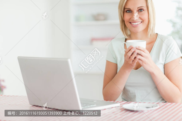 一個(gè)拿著咖啡的女人在她面前看著廚房里的攝像機(jī)