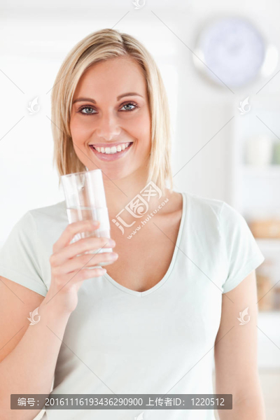 微笑的女人拿著一杯水看著相機