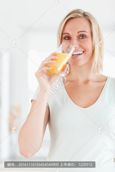 可愛的女人喝橙汁看相機