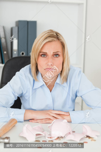 生悶氣的女人坐在一個破碎的撲滿看著相機在她的辦公室前