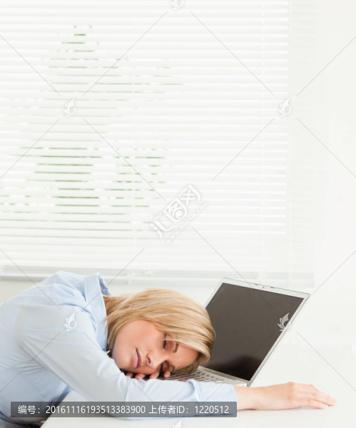 可愛的金發(fā)碧眼的女商人睡在她的筆記本保溫杯