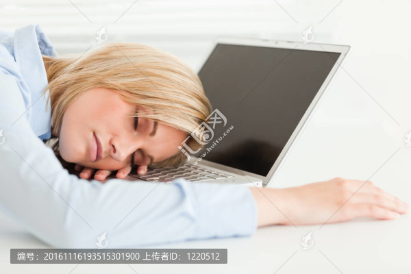 可愛的金發(fā)女人睡在她的筆記本上拿著一杯咖啡