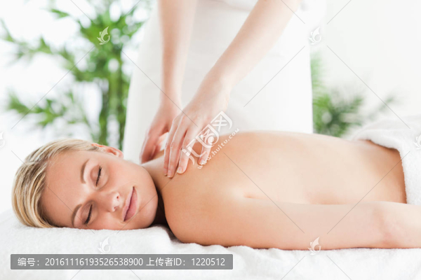 美麗的女人在躺椅放松按摩時，眼睛在健康中心關閉