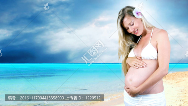 幸福的孕婦在陽光明媚的熱帶沙灘上