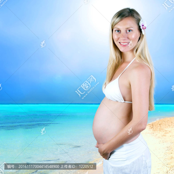 幸福的孕婦在陽光明媚的熱帶沙灘上