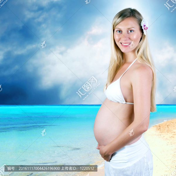 幸福的孕婦在陽光明媚的熱帶沙灘上