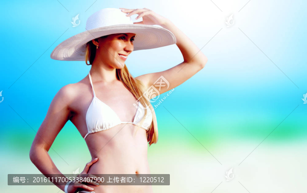 在比基尼和白帽子在陽光明媚的熱帶海灘的年輕漂亮的女人
