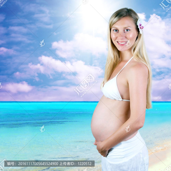幸福的孕婦在陽光明媚的熱帶沙灘上