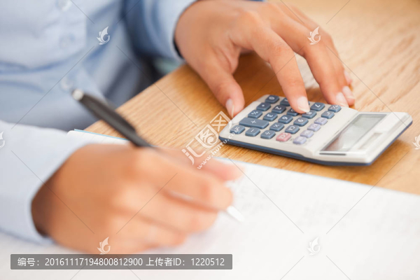 使用鋼筆和計算器的女性手