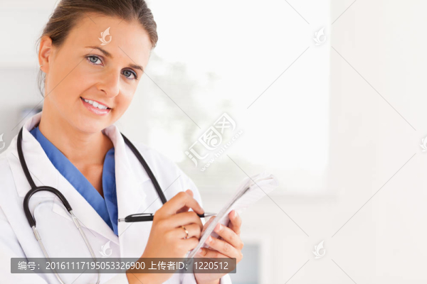 靠近一個微笑的女醫(yī)生寫的東西，看著相機在手術(shù)