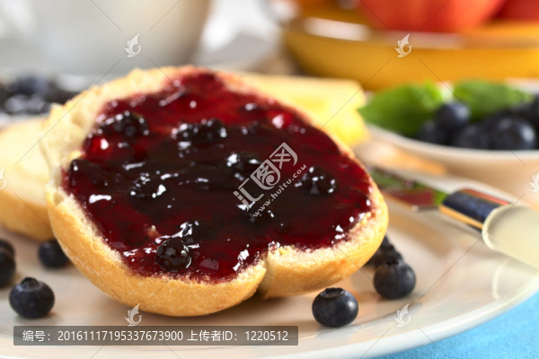 藍莓果醬半個半甜面包，新鮮藍莓和其他水果和一個杯子在后面（選擇性重點；重點在左前方的果醬和饅頭）