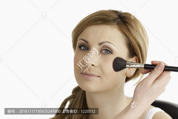 化妝師化妝申請(qǐng)一個(gè)迷人的金發(fā)女人在工作室