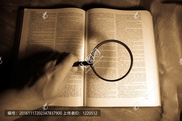 放大鏡；書和人的手。
