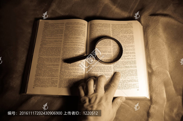 放大鏡；書和人的手。