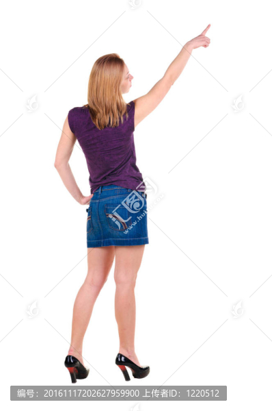 美麗的年輕女子在衣服指著墻壁。后視圖。
