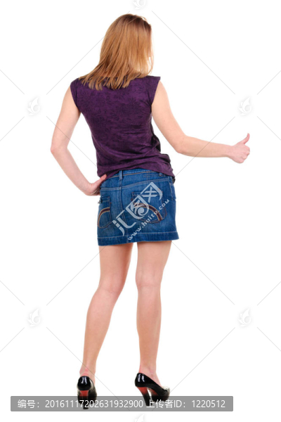 美麗的年輕女子在衣服指著墻壁。后視圖。