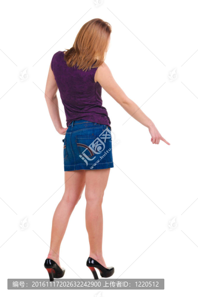 美麗的年輕女子在衣服指著墻壁。后視圖。