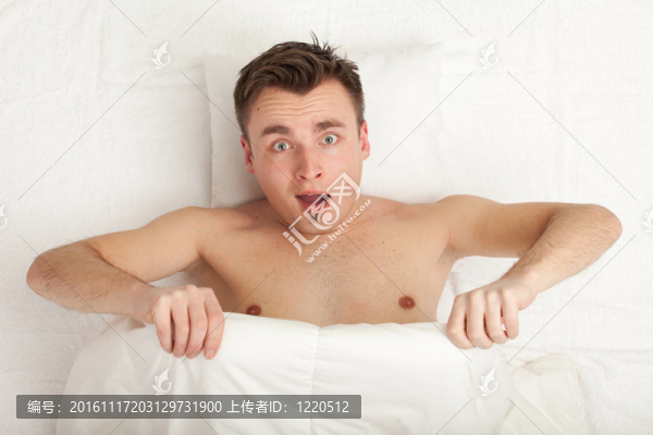 驚喜的年輕帥哥在白色床上用品；系列