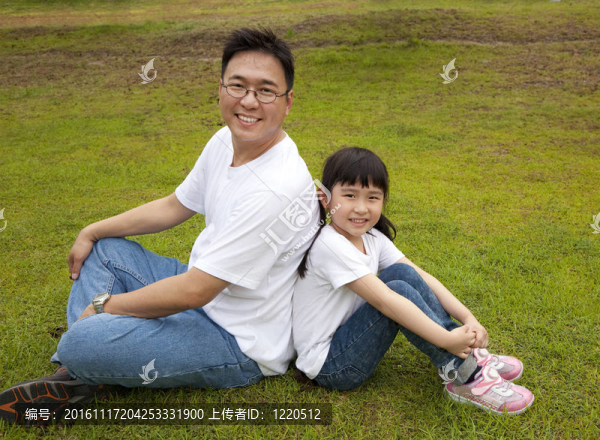 快樂的父親和女兒坐在草地上