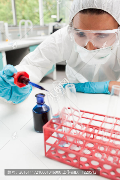 一個受保護的科學(xué)學(xué)生在實驗室中在試管中滴藍色液體的肖像