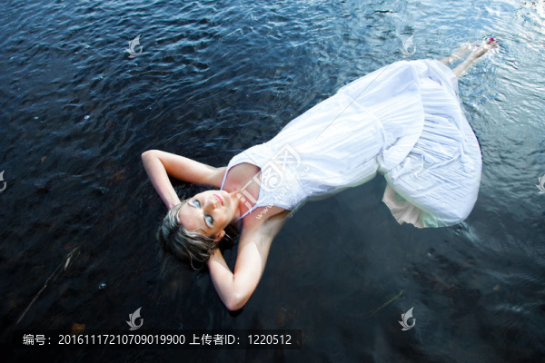 美麗的女人在初夏清晨漂浮在藍(lán)色河流中的沉默與孤獨
