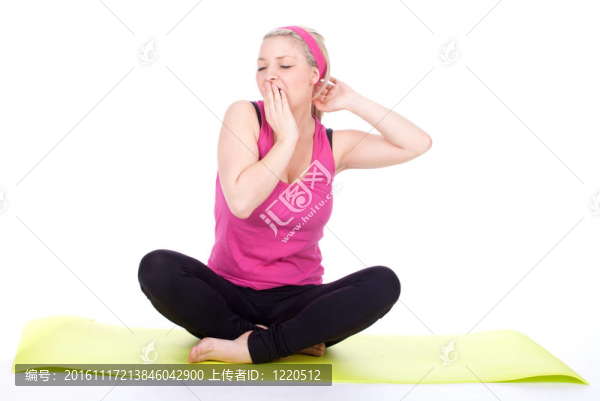 穿著粉色襯衫坐著交叉腿的打呵欠的年輕運動婦女