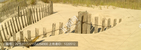 靠近海灘侵蝕圍欄的精靈燈。全景格式，焦點(diǎn)柵欄和神燈。顏色是溫暖的。砂埋燈底座。