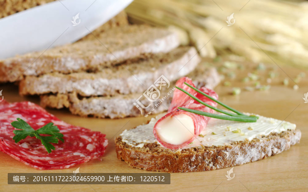 滾意大利臘腸片和奶油奶酪和半片黑面包上木板和配料韭菜（選擇性聚焦；對輥在前面包片和意大利臘腸前焦點