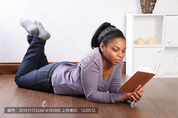 美麗的女孩在家里在地板上看書