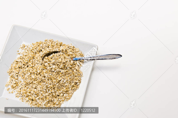 在白色背景上用湯匙舀干燕麥片
