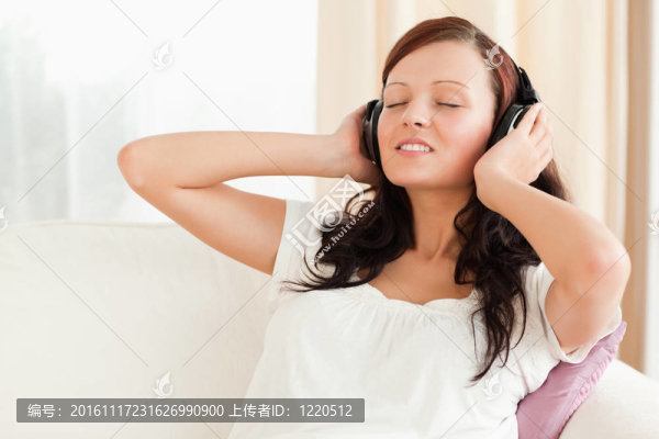 黑發(fā)女子在沙發(fā)上用耳機(jī)放松