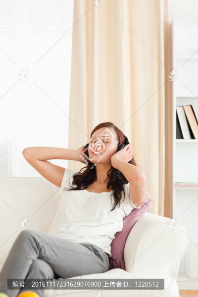 美麗的紅發(fā)女人在沙發(fā)上聽(tīng)音樂(lè)