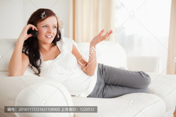 紅頭發(fā)的女人在沙發(fā)上打電話，放松