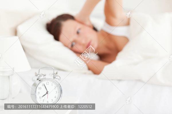 漂亮的紅發(fā)女人躺在床上不想聽(tīng)到鬧鐘