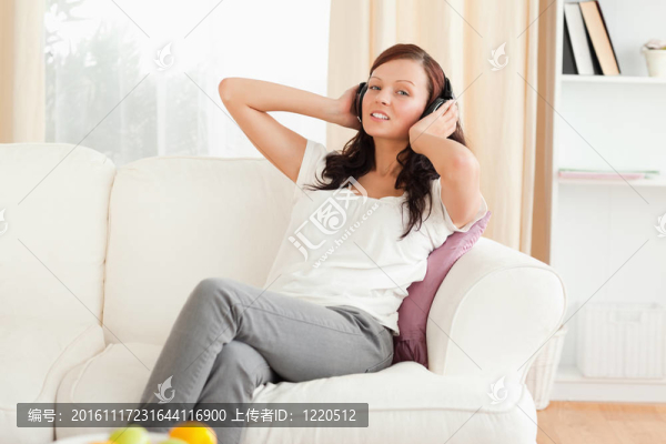 華麗的紅發(fā)女人在沙發(fā)上放松聽(tīng)音樂(lè)
