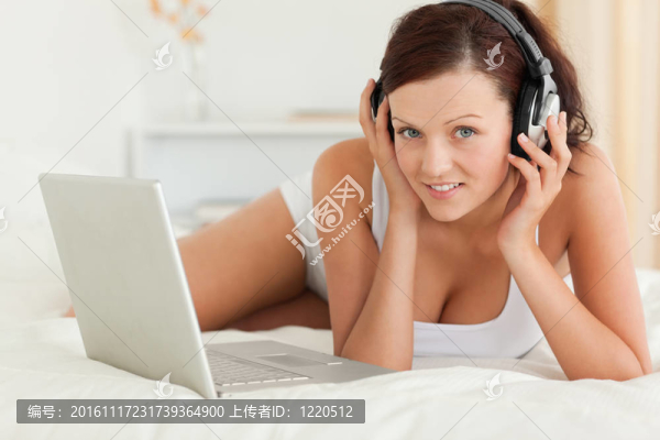 女人聽音樂工作在筆記本電腦看相機在臥室里