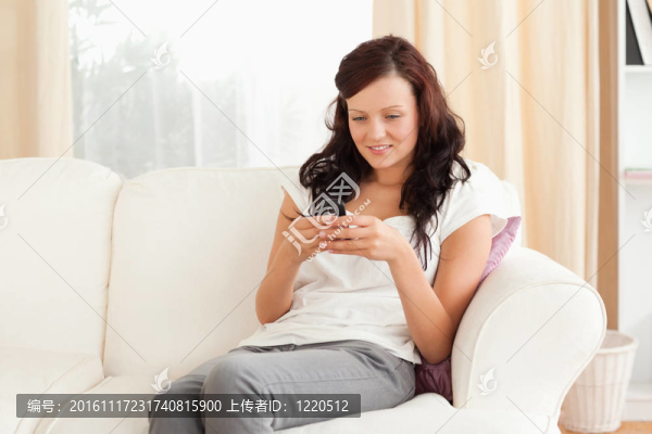 坐在沙發(fā)上邊發(fā)邊發(fā)短信的女人