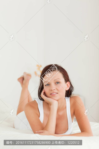 可愛的放松女人在床上看著相機(jī)