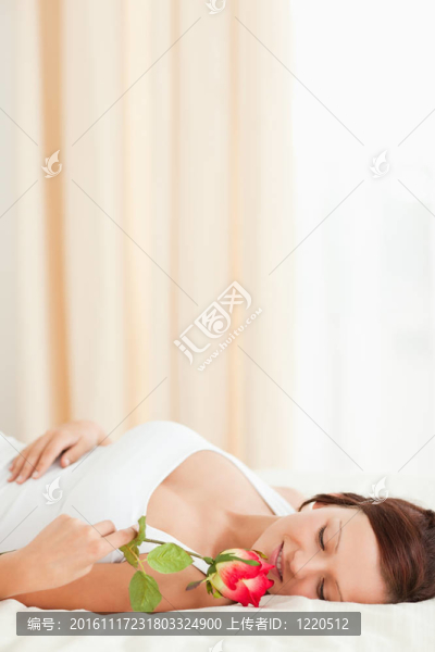 躺在床上的一朵玫瑰花的女人