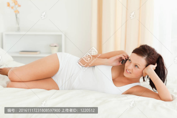 迷人的女人在床上打電話