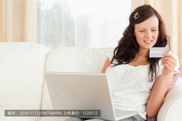 一個(gè)帶著筆記本電腦和一張卡片的年輕女人