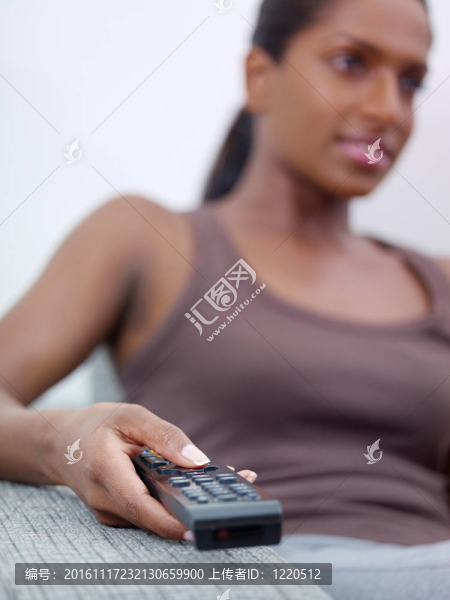 持遙控器和看電視的婦女