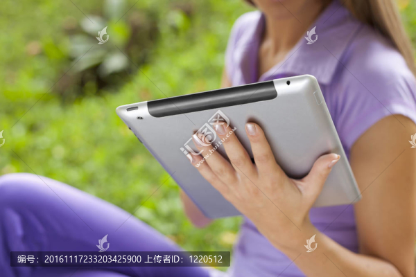 公園里美麗的年輕女性手上的平板電腦